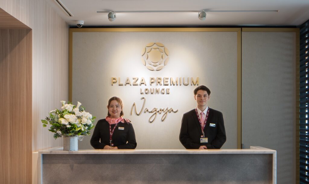 The front desk of the Plaza Premium Lounge Nagoya with two receptionists standing behind it