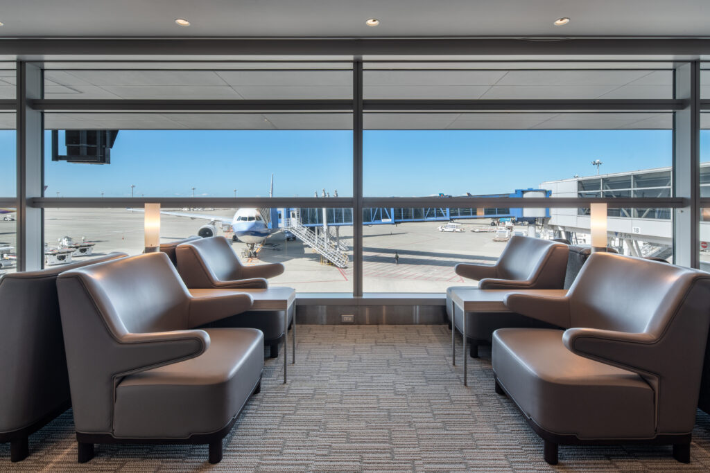 Grey seating by the departure gate with the runway in the background