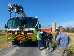 An image of people inspecting an Oshkosh striker vehicle outside in a field