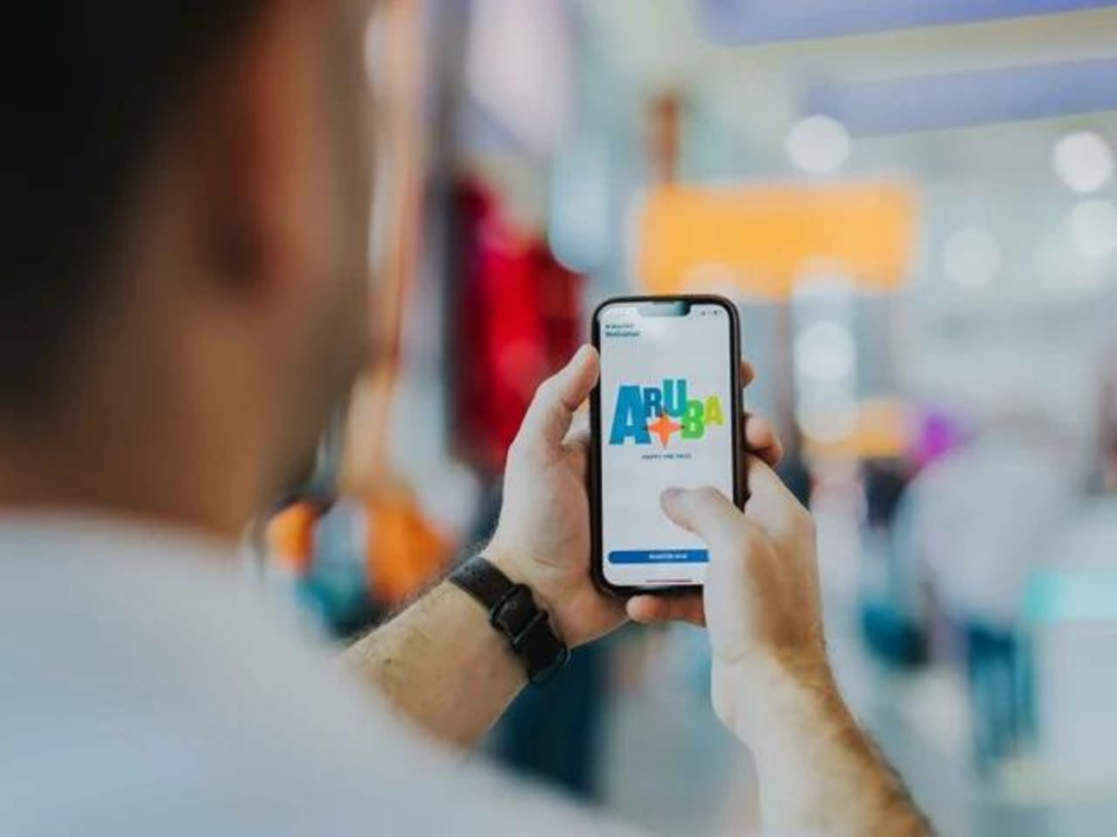 A man holds up his phone, it's displaying the Aruba logo