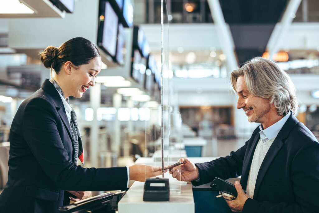 An airline worker hands a passport back to a smiling passenger