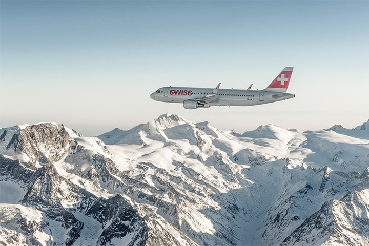 A SWISS plane flying over snowy mountains