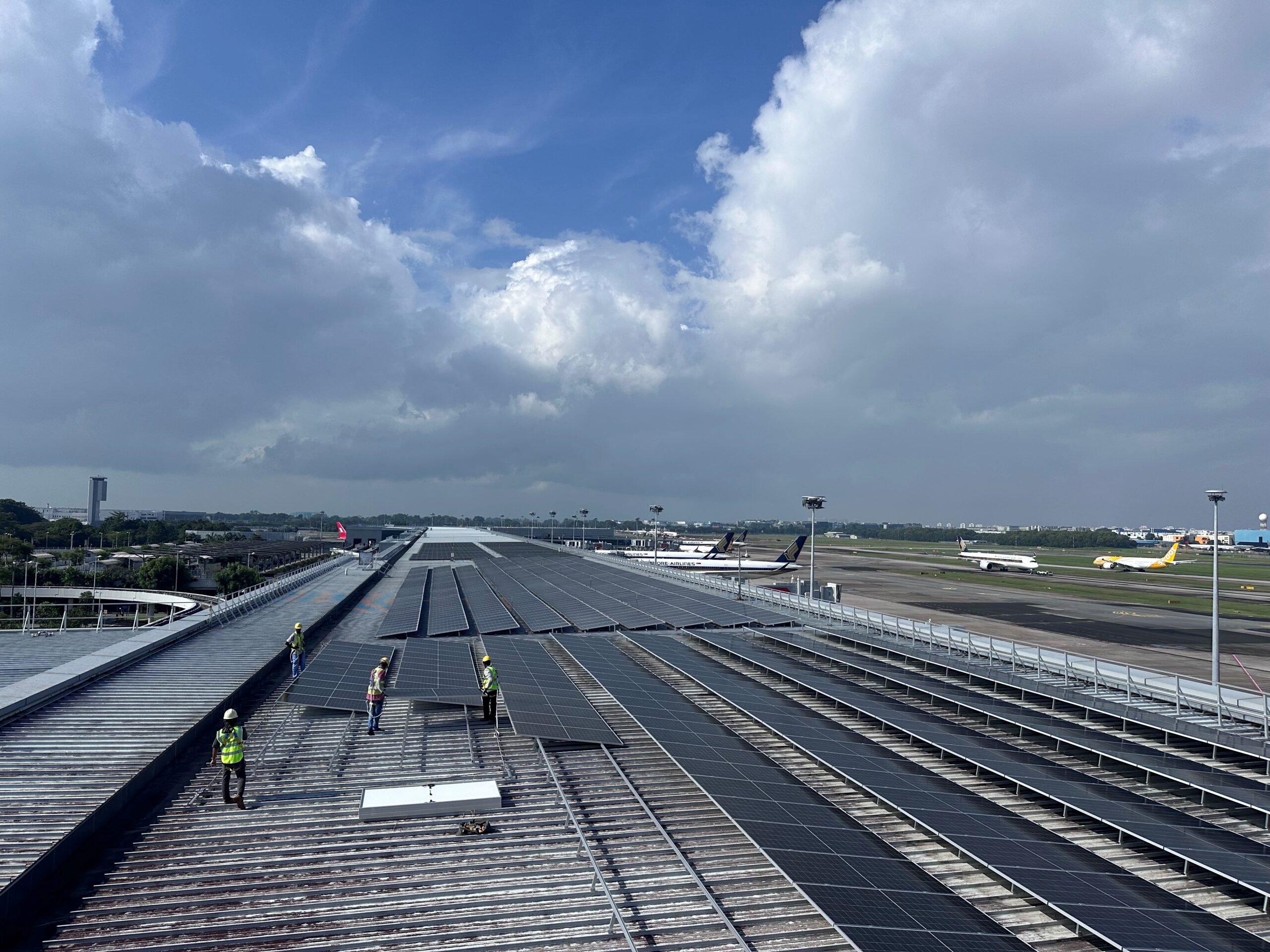 Workers installing solar panels on the Terminal 3 rooftop