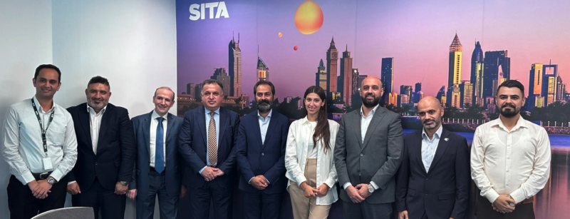 A group of people stood in front of an image of the Baghdad skyline