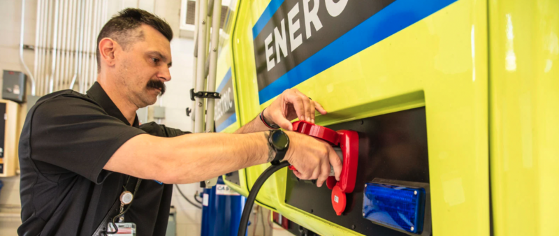 A male worker charging a yellow and black electric vehicle