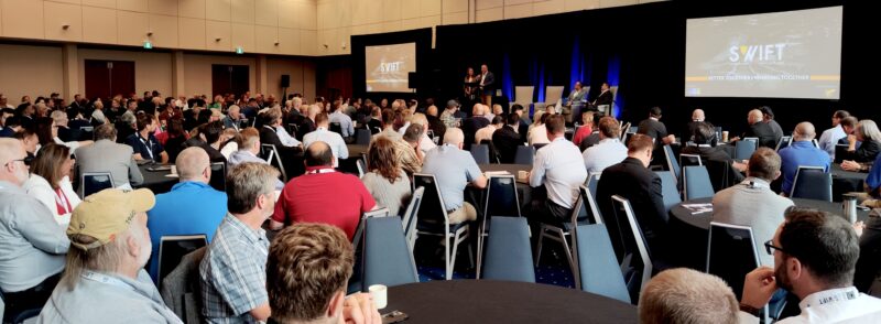 A crowd of people sat listening to the opening plenary at the SWIFT conference