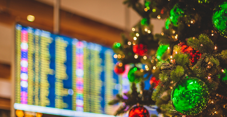 Decorated Christmas tree in an airport terminal, arrivals/departures board in the background