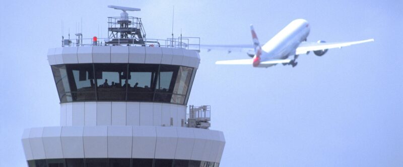 ATC control tower in the foreground, jet taking off in the background