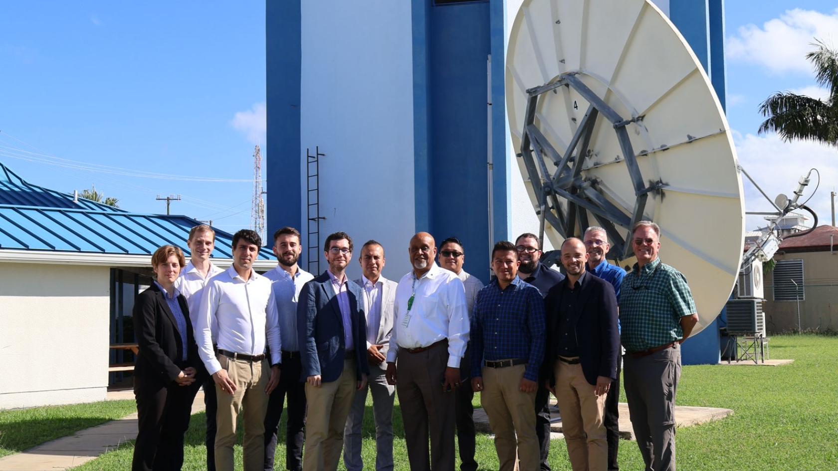 People stood in a row in front of a satellite dish