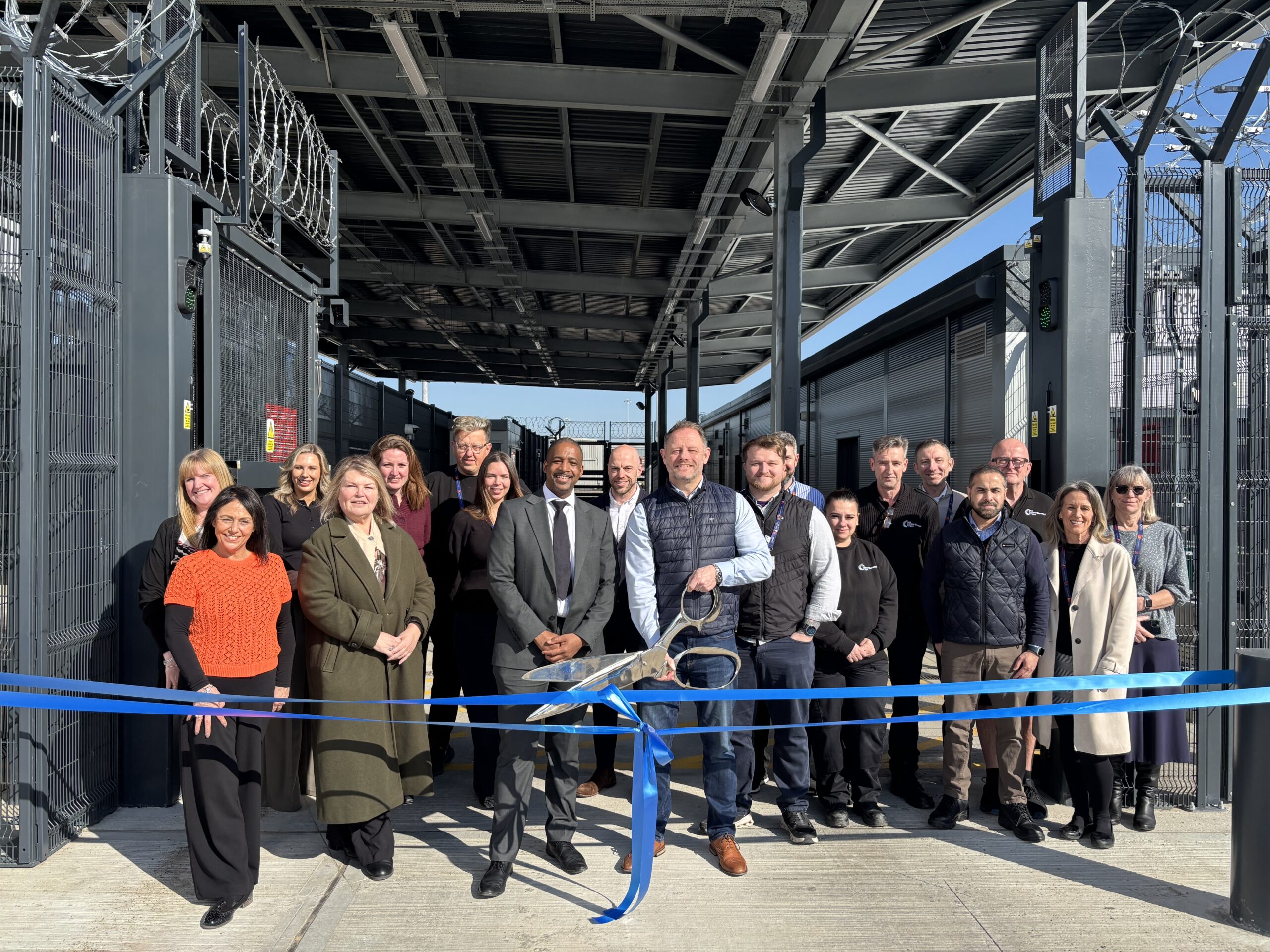 A group of people cutting a ribbon with massive scissors