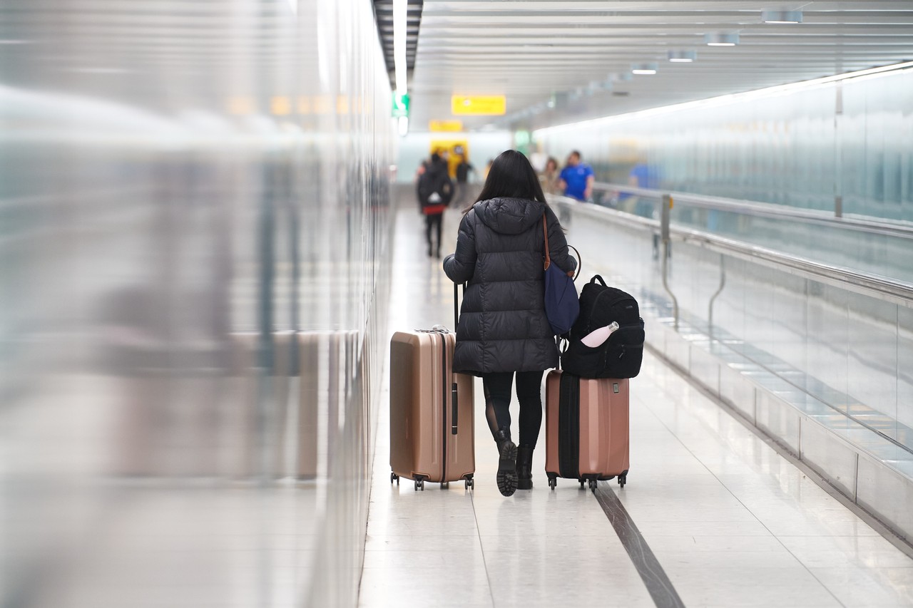 A passenger with luggage walks next to a travelator in a London Heathrow Airport Central Terminal Area