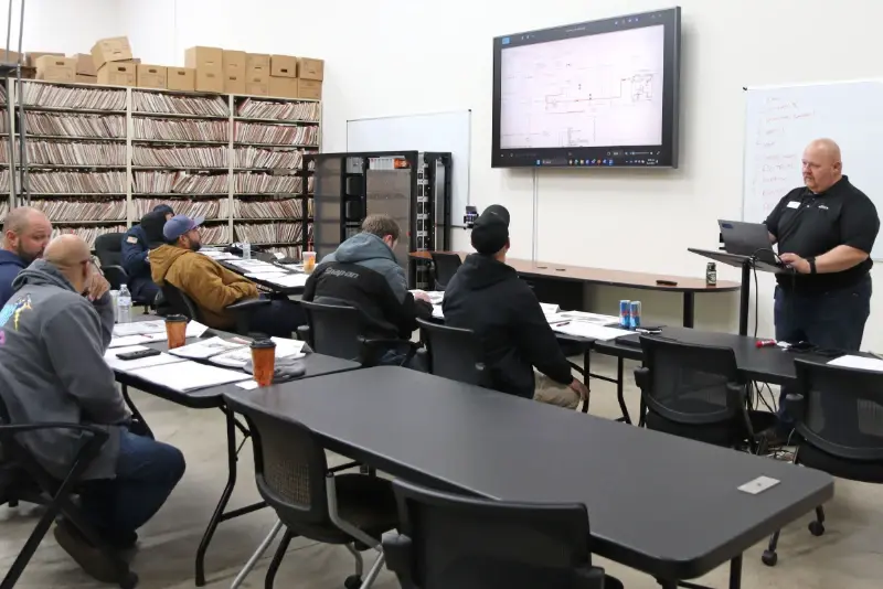 An instructor presents a schematic to technicians during an ARFF technical training classroom session