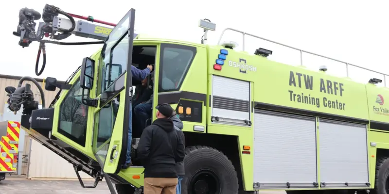 Technicians boarding an Oshkosh Striker ARFF vehicle at the ATW ARFF Training Center during a maintenance training session