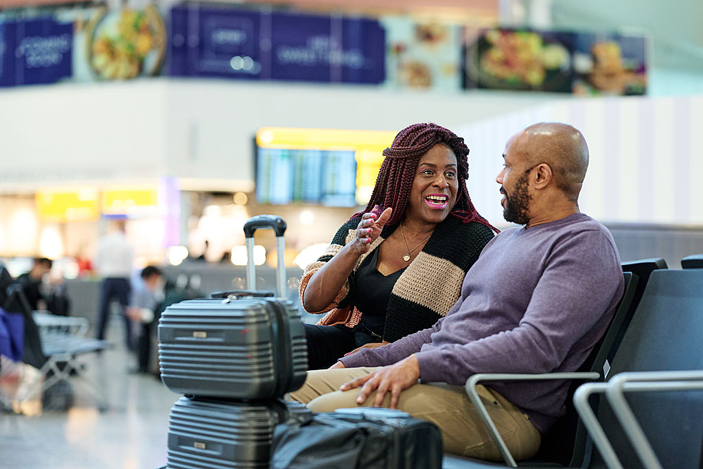 Couple sitting in Terminal 2, chatting. A man and woman sitting on luggage at an airport.