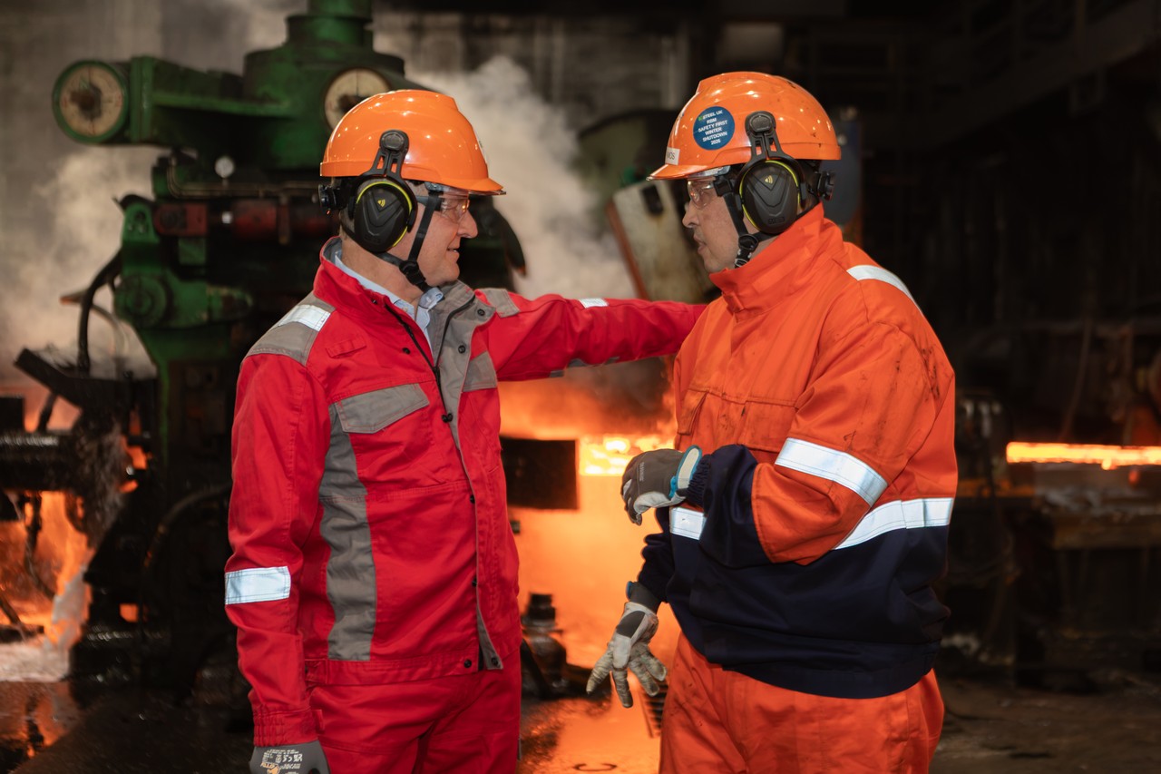 Two men talking in front of a furnace